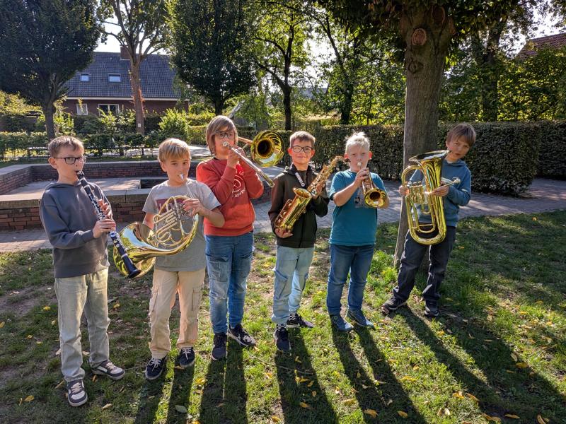 Kinder spielen Blechblasinstrumente im Schulgarten