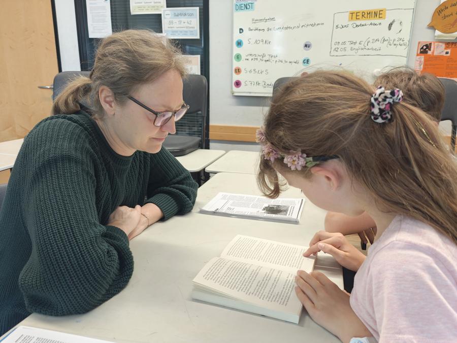 Lehrerin liest gemeinsam mit einer Schülerin
