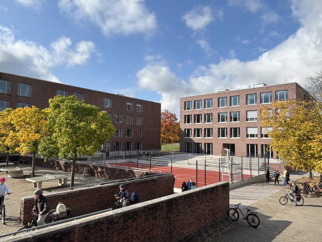 Neubau des MSMG mit Sportplatz unter blauem Himmel