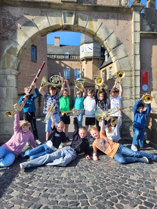 Orchesterkinder mit Instrumenten vor einem Torbogen